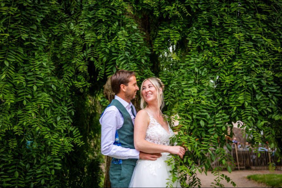 Couple embracing in front of a lush green hedge