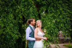 Couple embracing in front of a lush green hedge