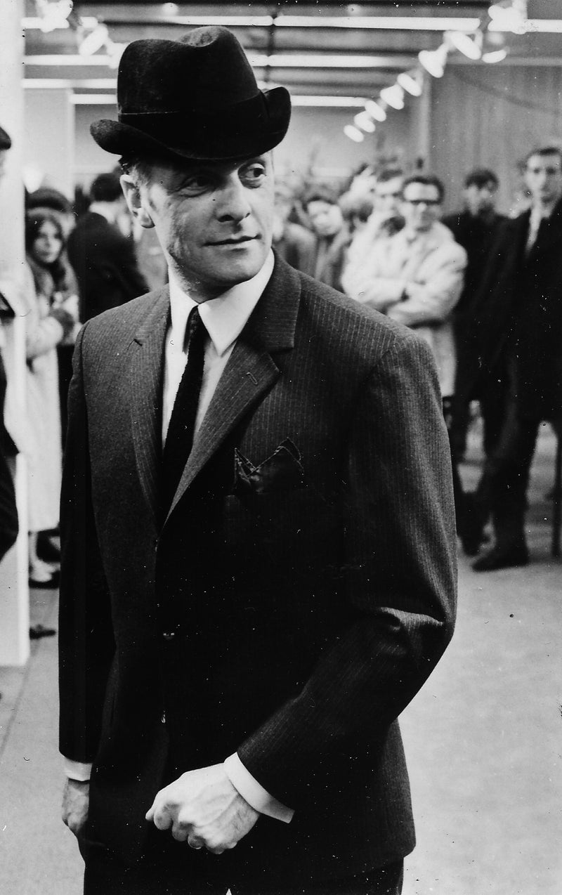 Archive photograph of Wim Possen in a pinstripe suit and felt hat, a crowd behind him